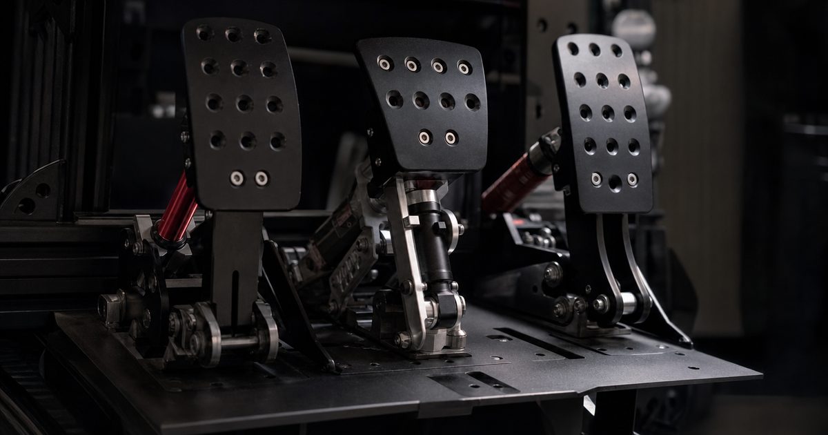 Close-up of a three-pedal sim-racing pedal set with a load-cell brake mounted on a black aluminium pedal plate.